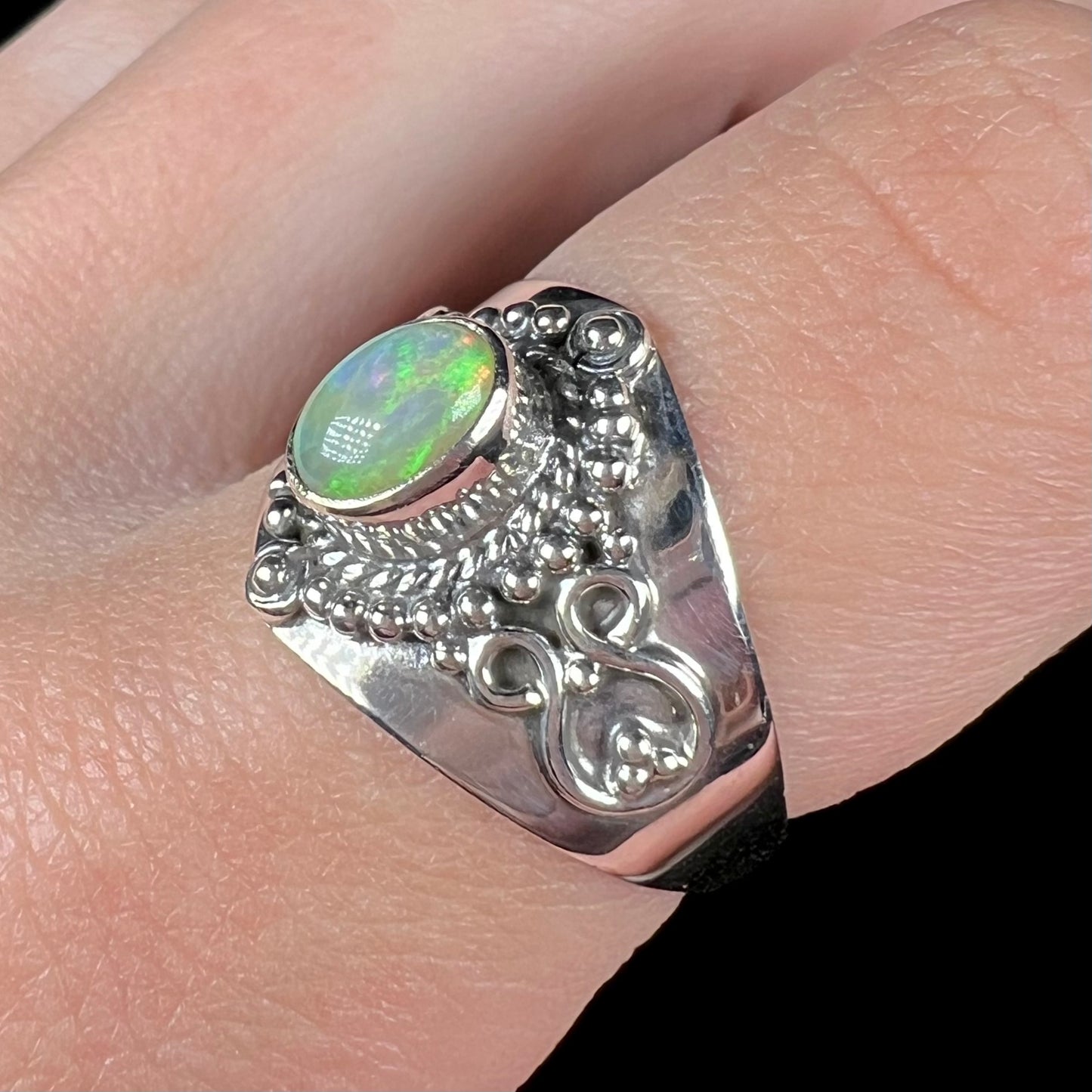 The side angle of a Boho opal ring, worn on a finger.