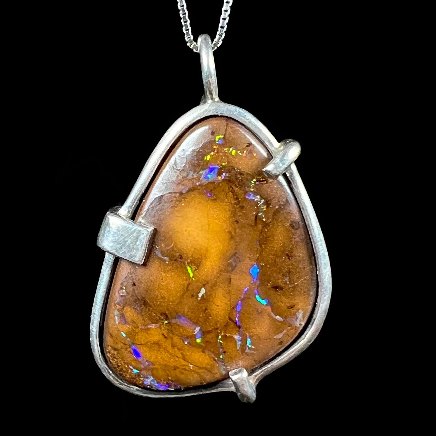 A handmade sterling silver pendant bezel and prong set with a natural boulder opal stone.
