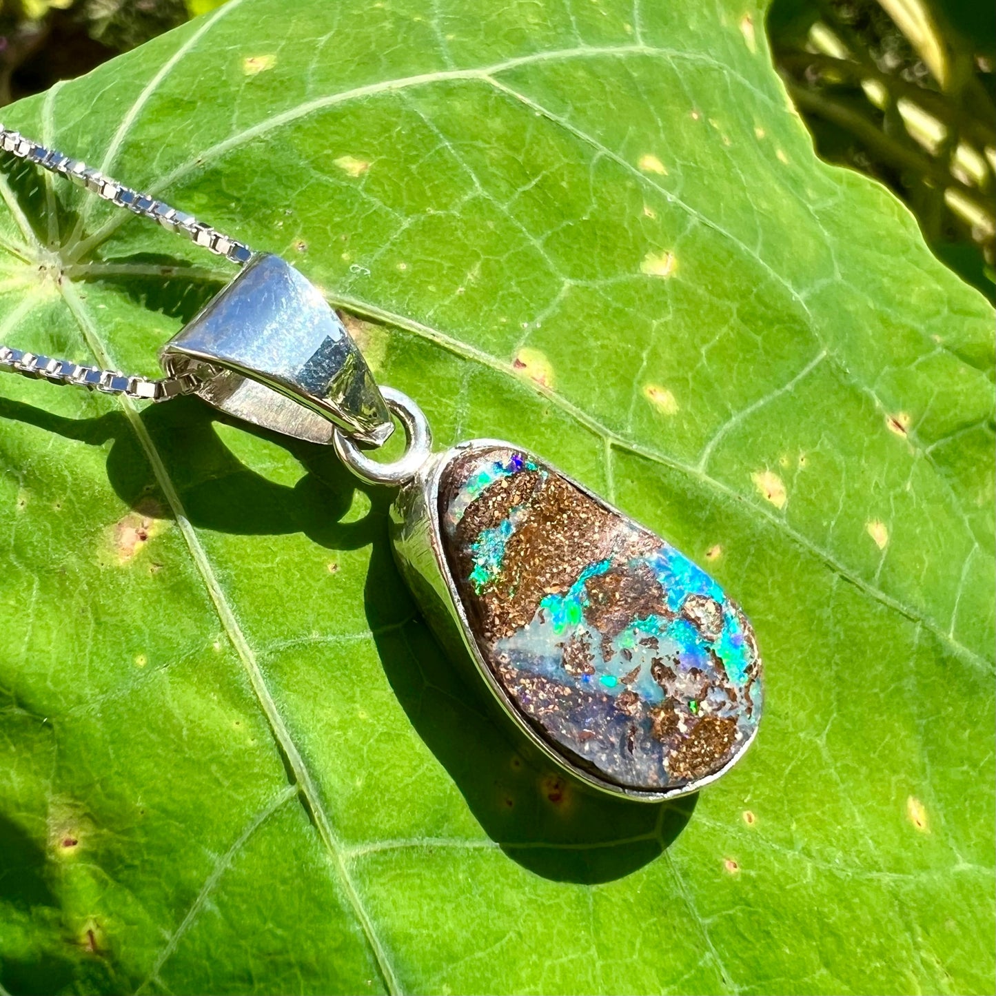 A sterling silver necklace set with a rainbow boulder opal stone.