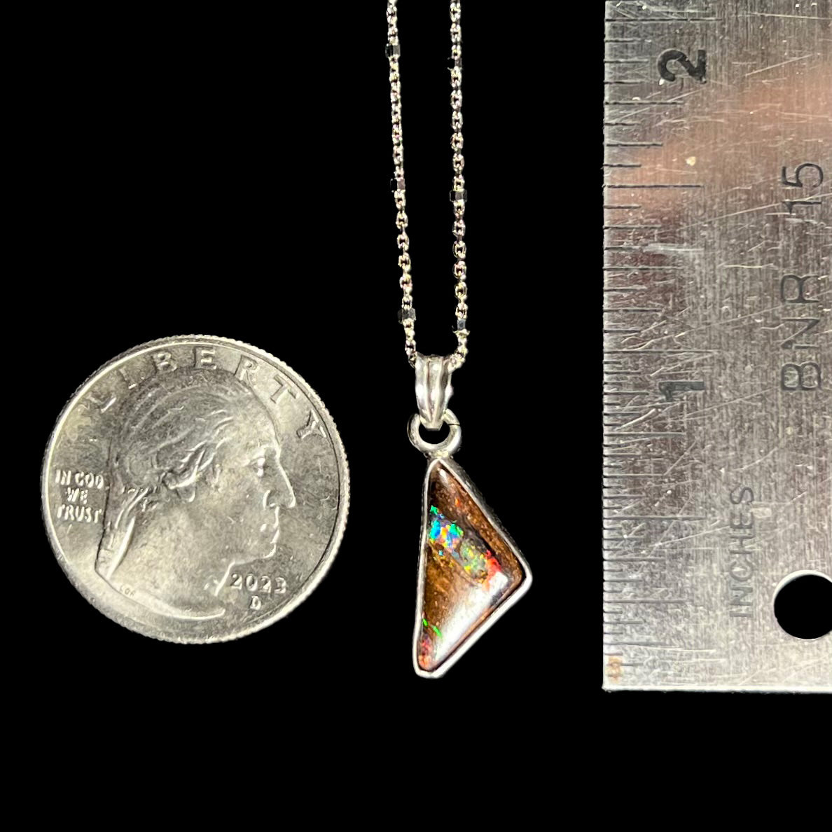 A triangle shaped opal necklace in sterling silver.  The opal shines with every color of the rainbow.