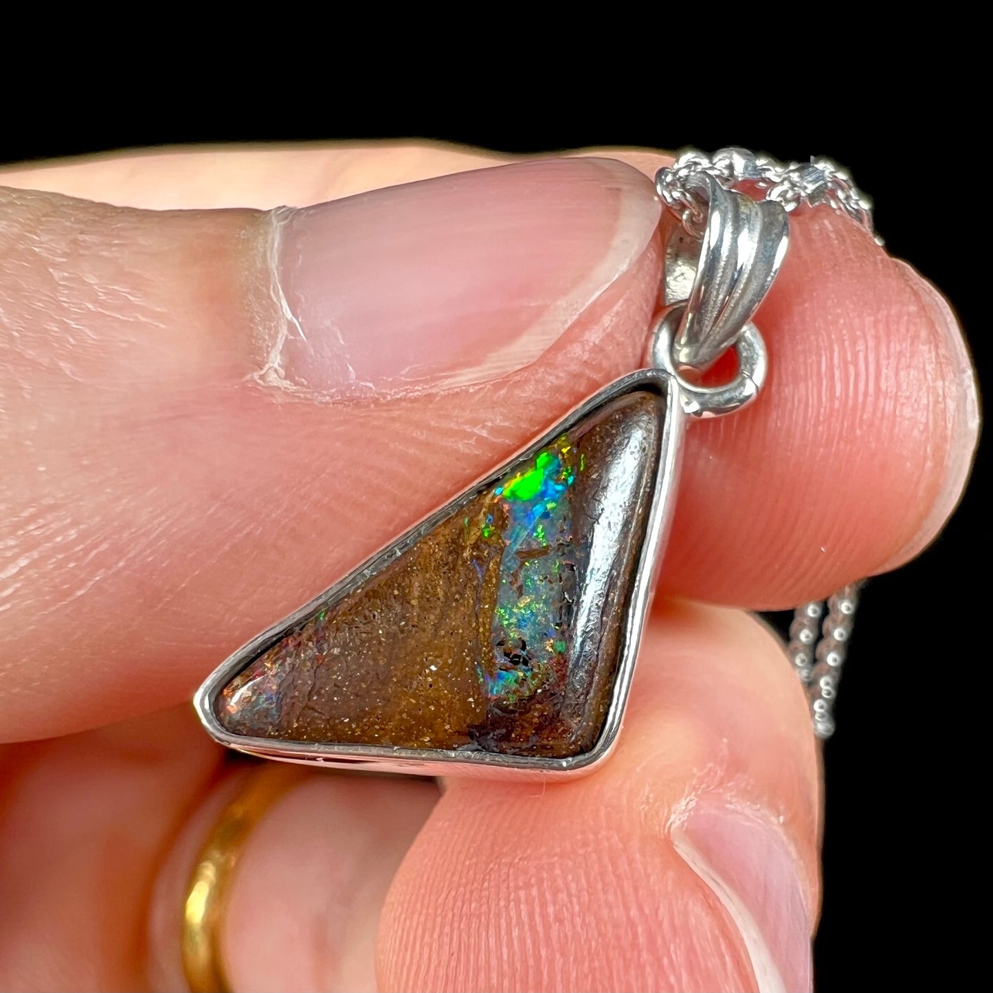 A triangle shaped opal necklace in sterling silver.  The opal shines with every color of the rainbow.