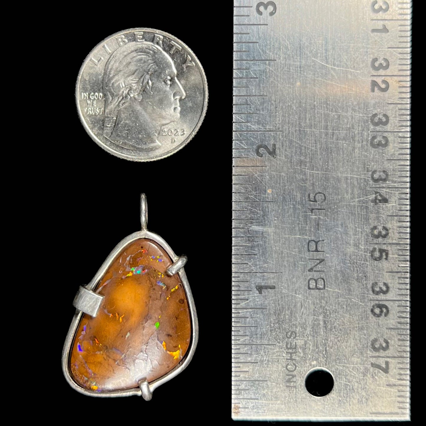 A handmade sterling silver pendant bezel and prong set with a natural boulder opal stone. The opal shines veins of color.