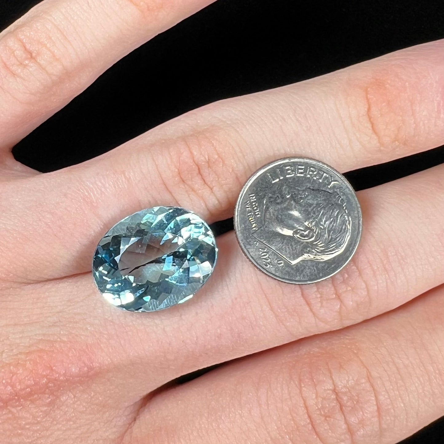 A loose, oval cut Brazilian aquamarine gemstone. The stone is a rich aqua blue color.