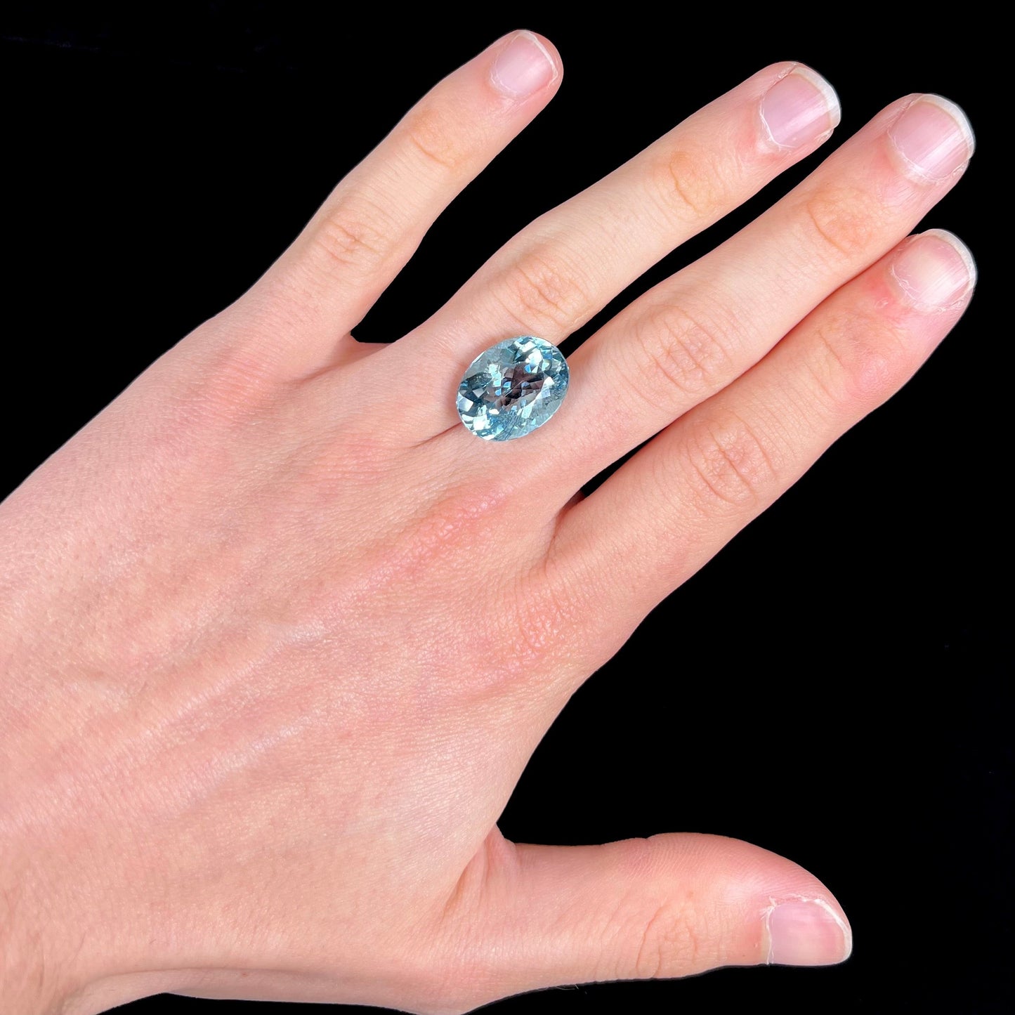 A loose, oval cut Brazilian aquamarine gemstone. The stone is a rich aqua blue color.