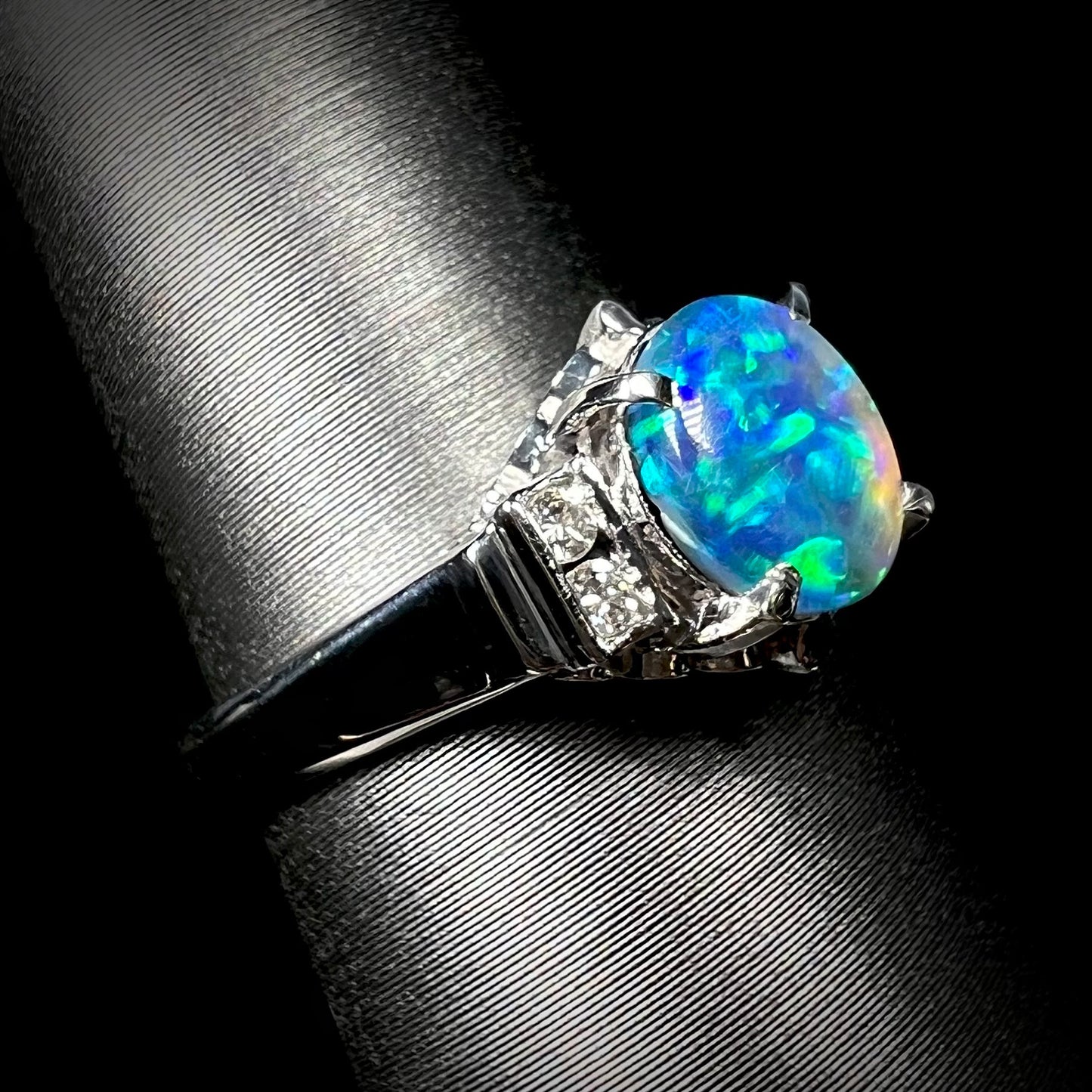 A Lightning Ridge black opal with bright green fire, mounted in a platinum engagement ring with diamonds.