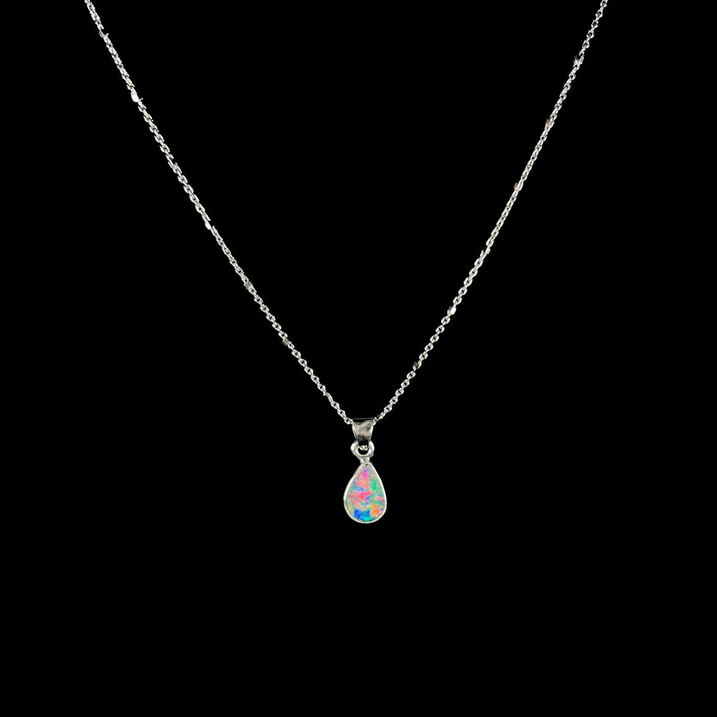 A pear shaped black opal necklace set in sterling silver. The opal vividly flashes every color of the rainbow.