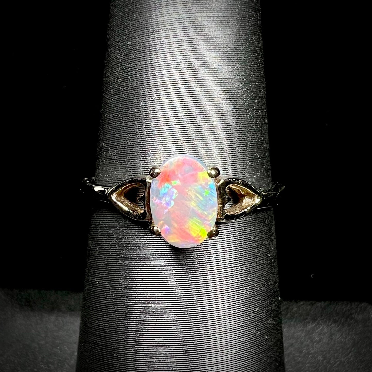 A dainty yellow gold ring mounted with a vivdly bright red Australian opal. The ring has two heart shaped designs.
