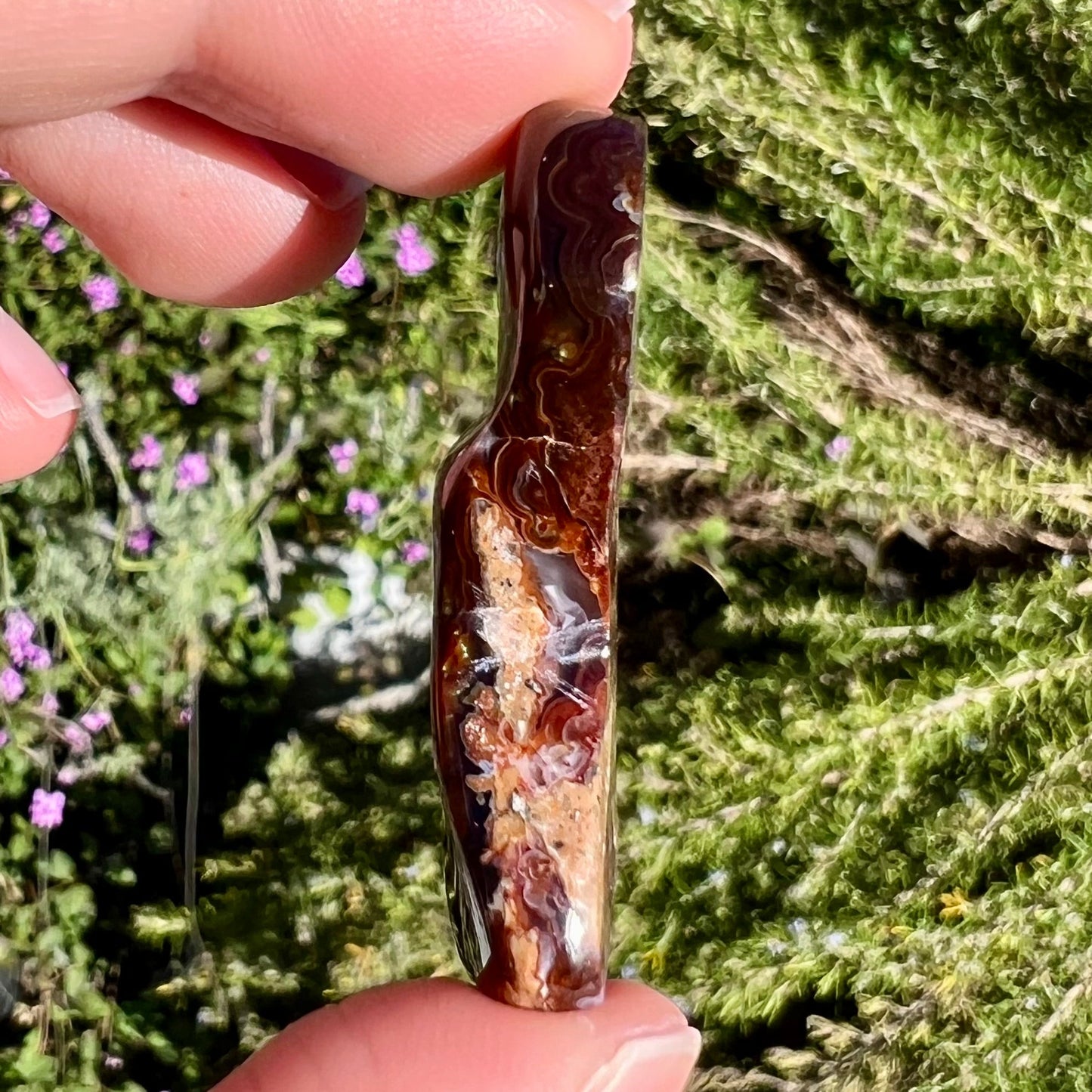 A loose, freeform cabochon cut fire agate gemstone. The stone exhibits a bubbly pattern.