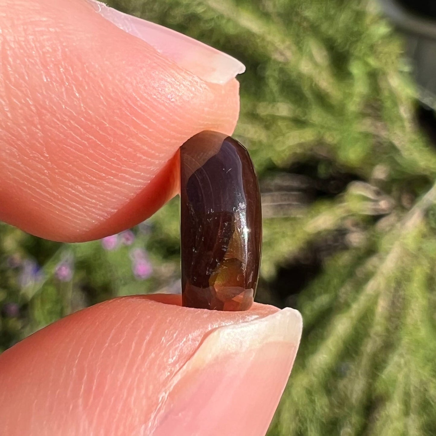 A loose, 3.38ct, pear shaped Mexican fire agate stone. The stone shines a vivid, bright green color with a purple streak.