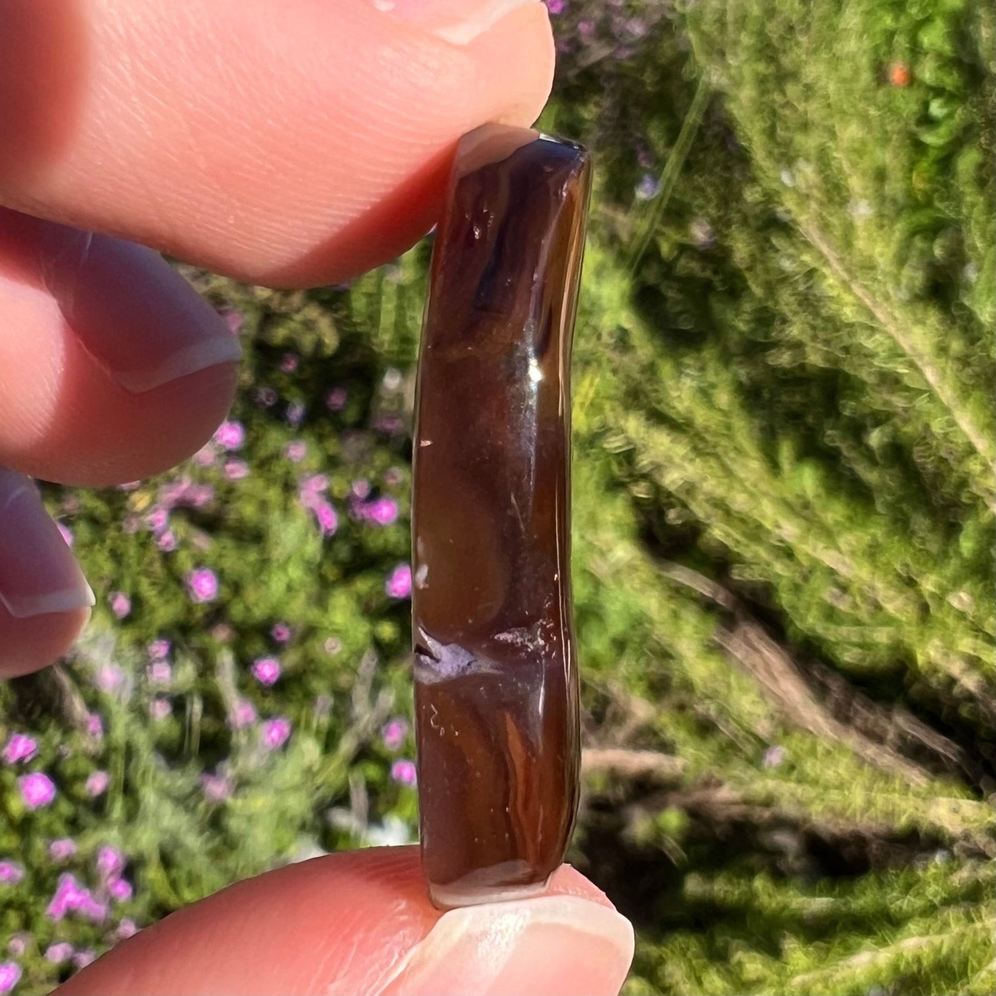 A loose fire agate cabochon.  The stone has iridescent green, yellow, and blue colors.