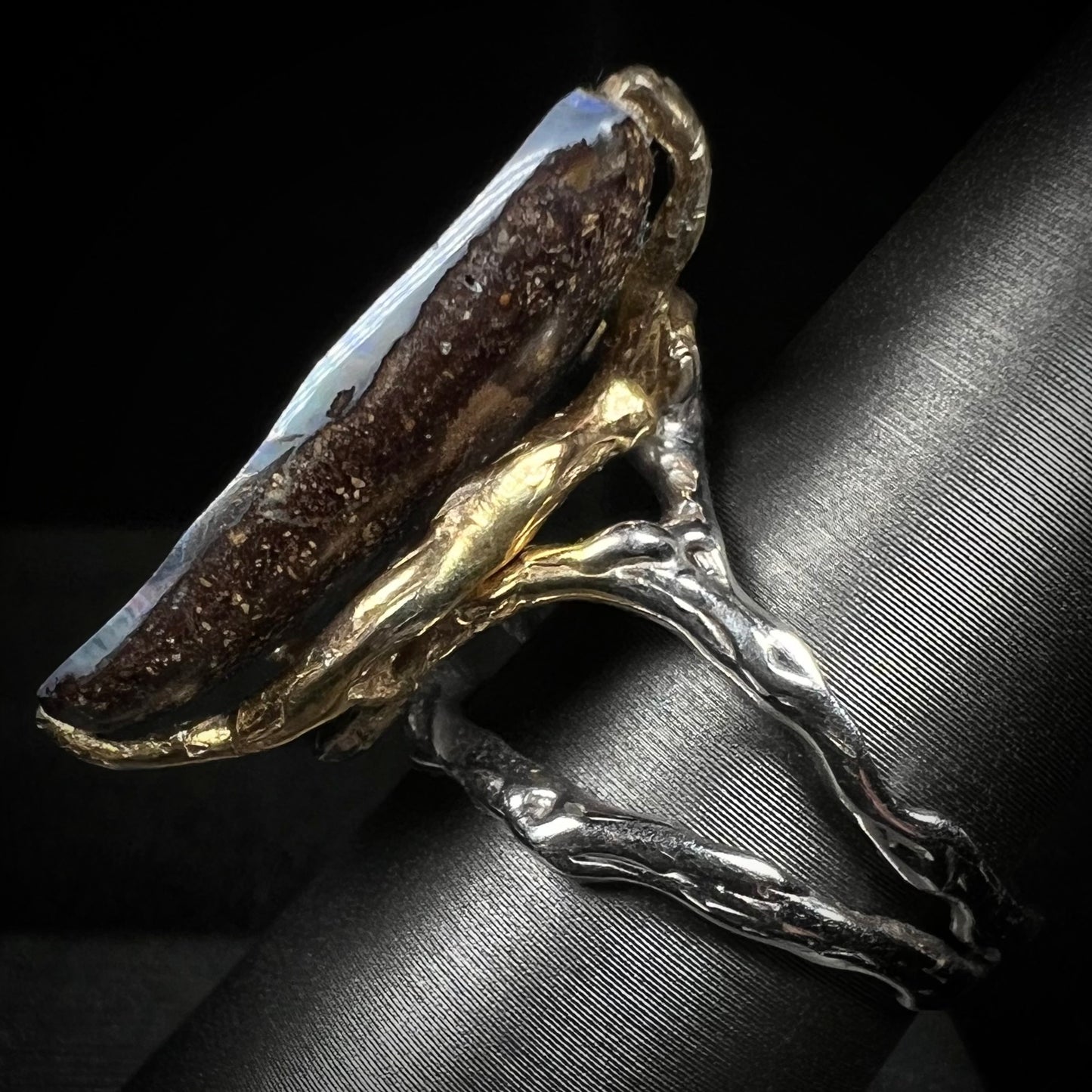 Side view of two-tone Brutalist style boulder opal ring. The shank is silver and the prongs are gold.
