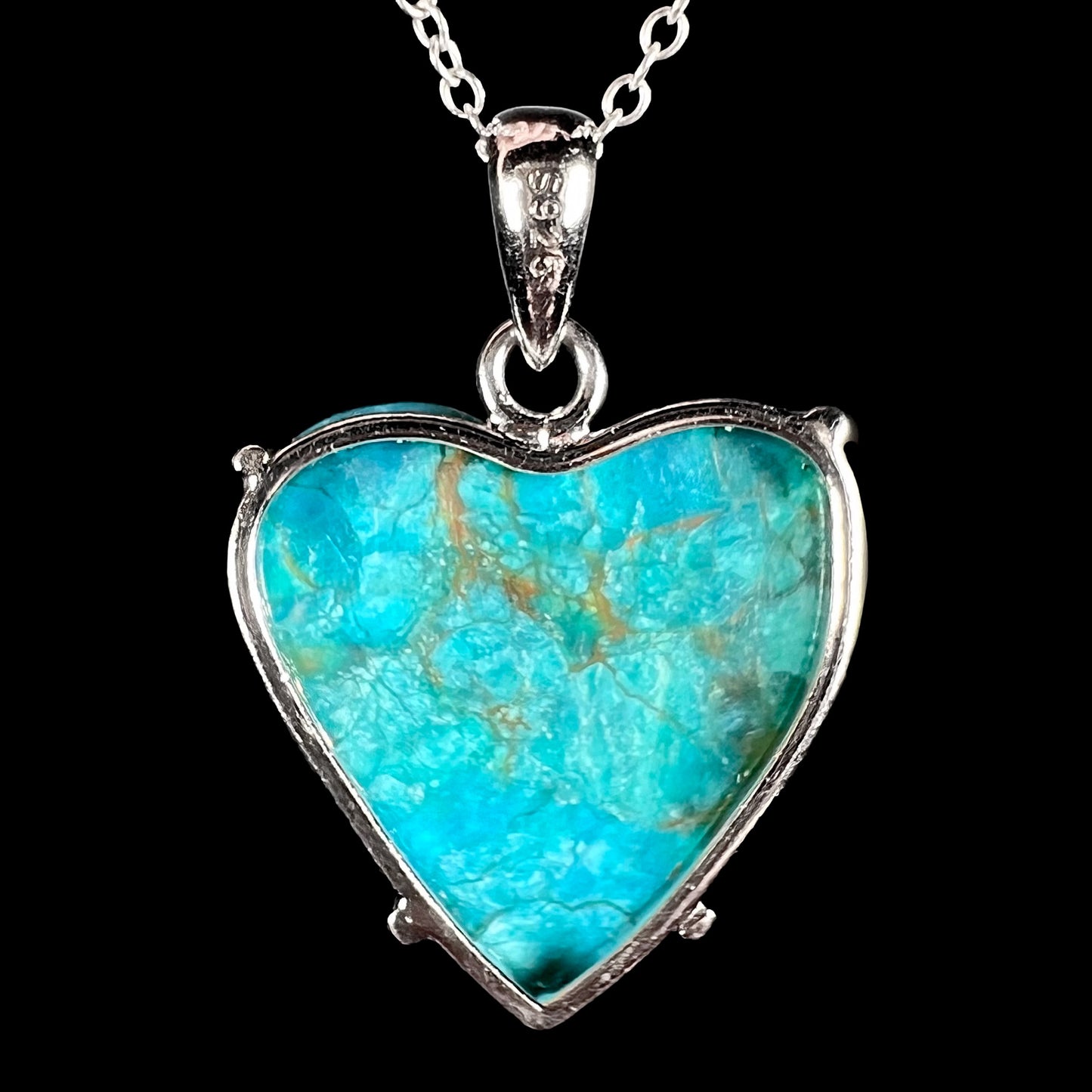 Backside of a heart-shaped Chilean blue opal pendant showing natural texture, silver frame, and “S925” stamp.