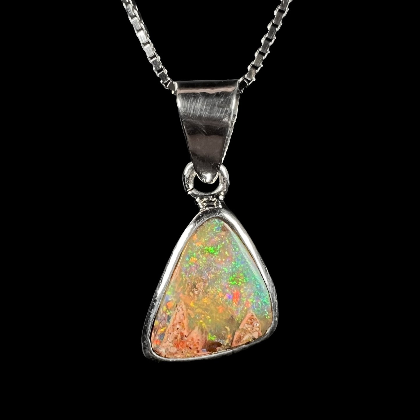 A sterling silver boulder opal necklace on a box chain. The opal twinkles bright red, green, and blue colors.