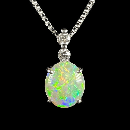 A Coober Pedy dark opal pendant set in platinum, displaying green, blue, and orange fire against a black background.
