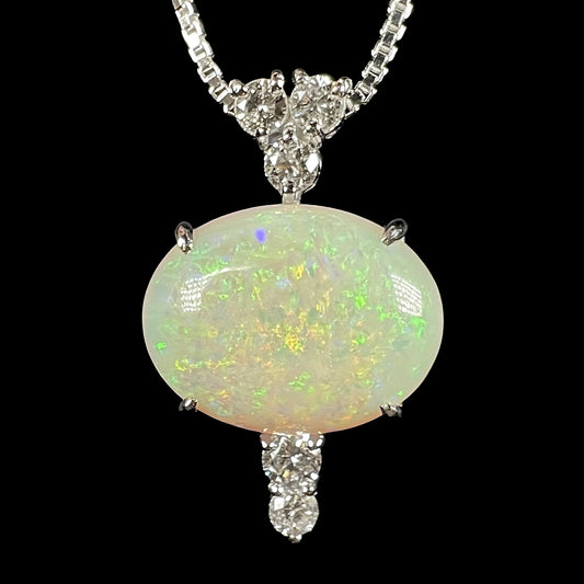 A Coober Pedy white opal and diamond platinum pendant with green and orange pinfire, captured in a macro front view against a black background.