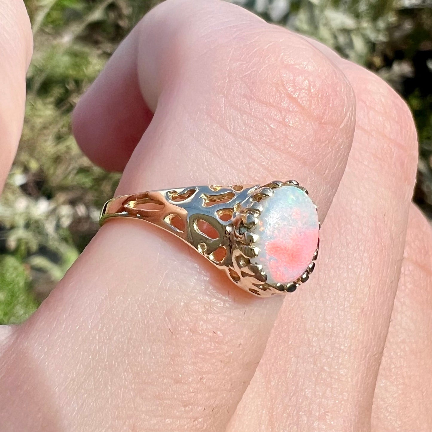 An organic-style yellow gold ring mounted with a natural Coober Pedy white opal. The opal has pink colors.