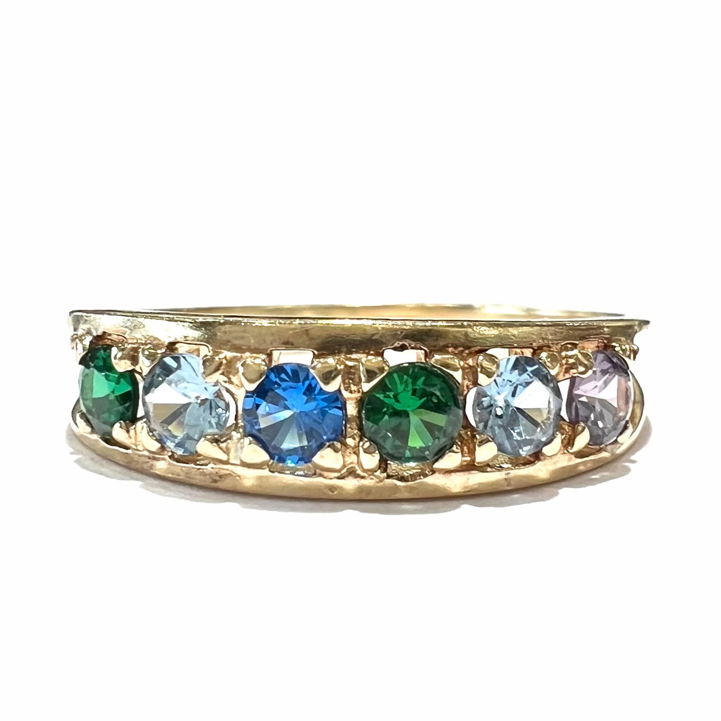 A ladies' yellow gold band set with green, dark blue, light blue, and light purple stones.