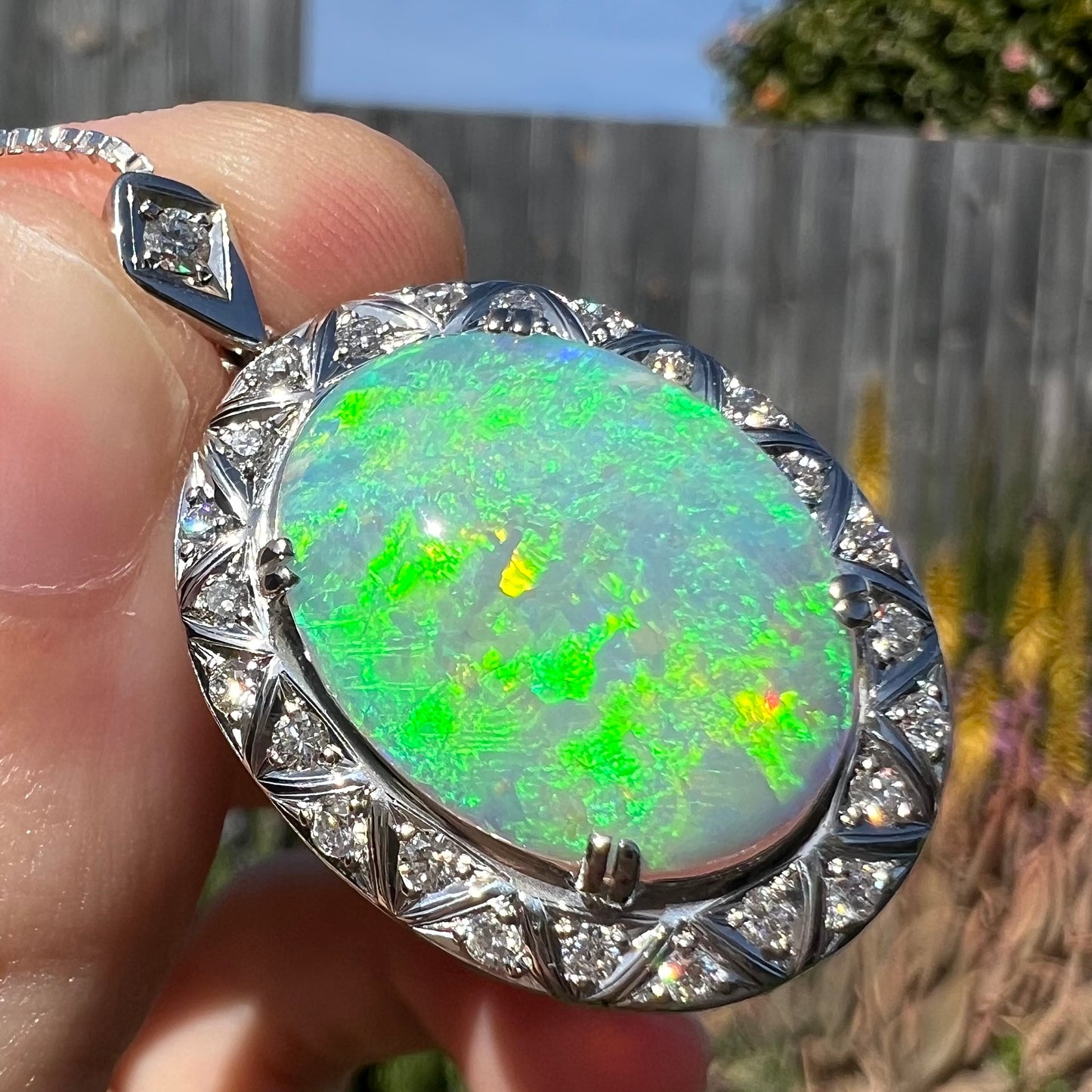Opposite side of pendant at slight angle, showing bright green flashes with hints of yellow and red.