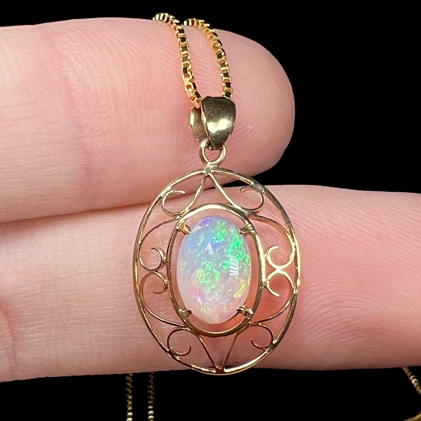 An 18 karat yellow gold filigree opal necklace. The opal has bright green color play.