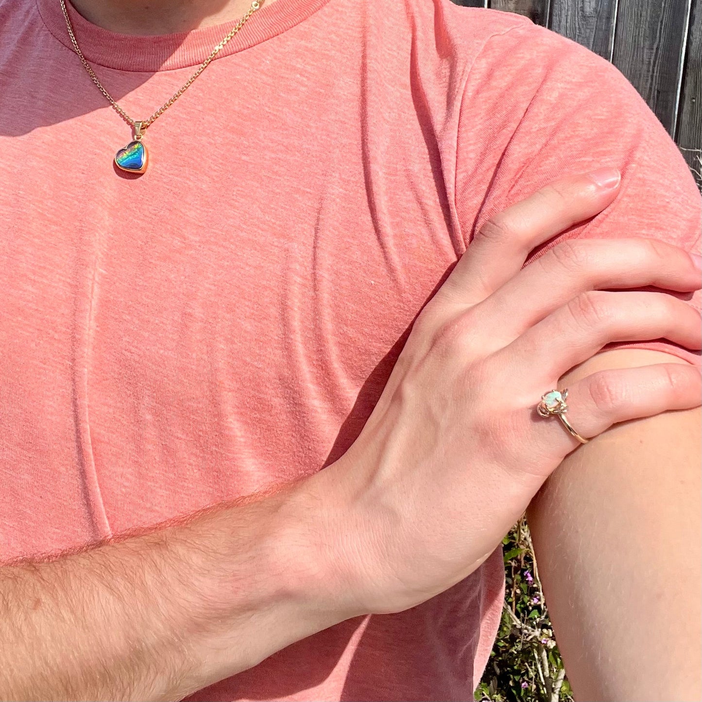 A yellow gold ring mounted with an oval cut opal. The opal has a white base tone with green and blue color play.