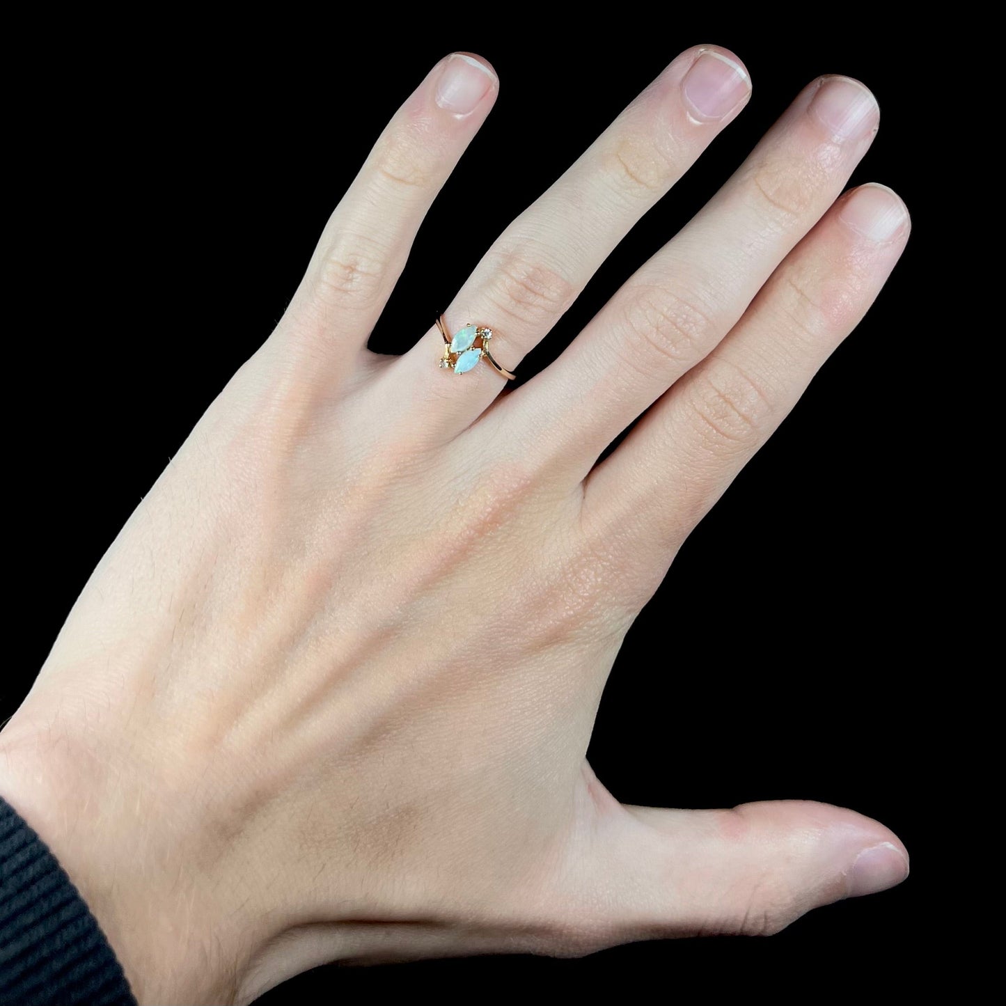 A ladies' gold ring mounted with two marquise cut opals and two diamond accents.