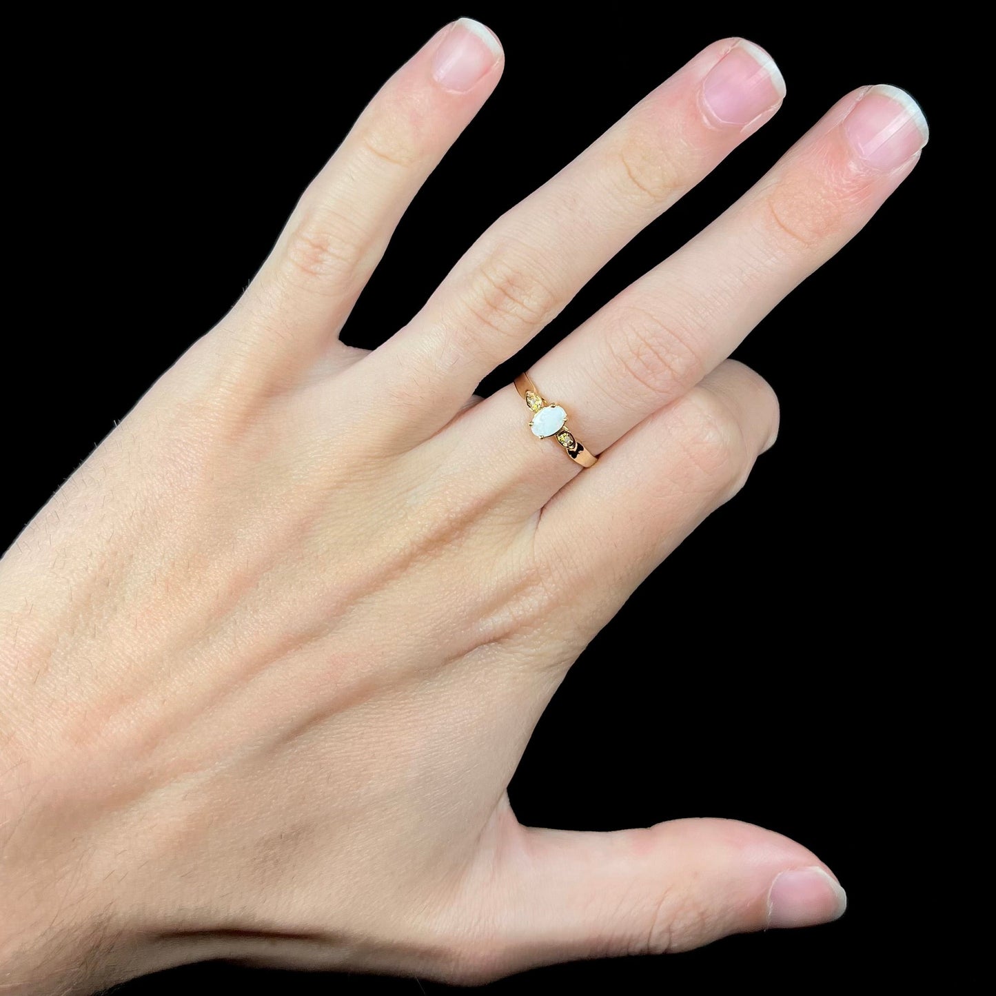 A dainty ladies' yellow gold opal and diamond ring. The opal has subtle play of color.