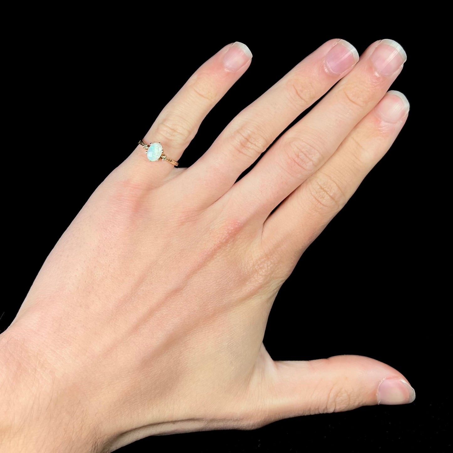 A dainty, 1960's style opal and diamond engagement ring. The ring is prong-set and yellow gold.