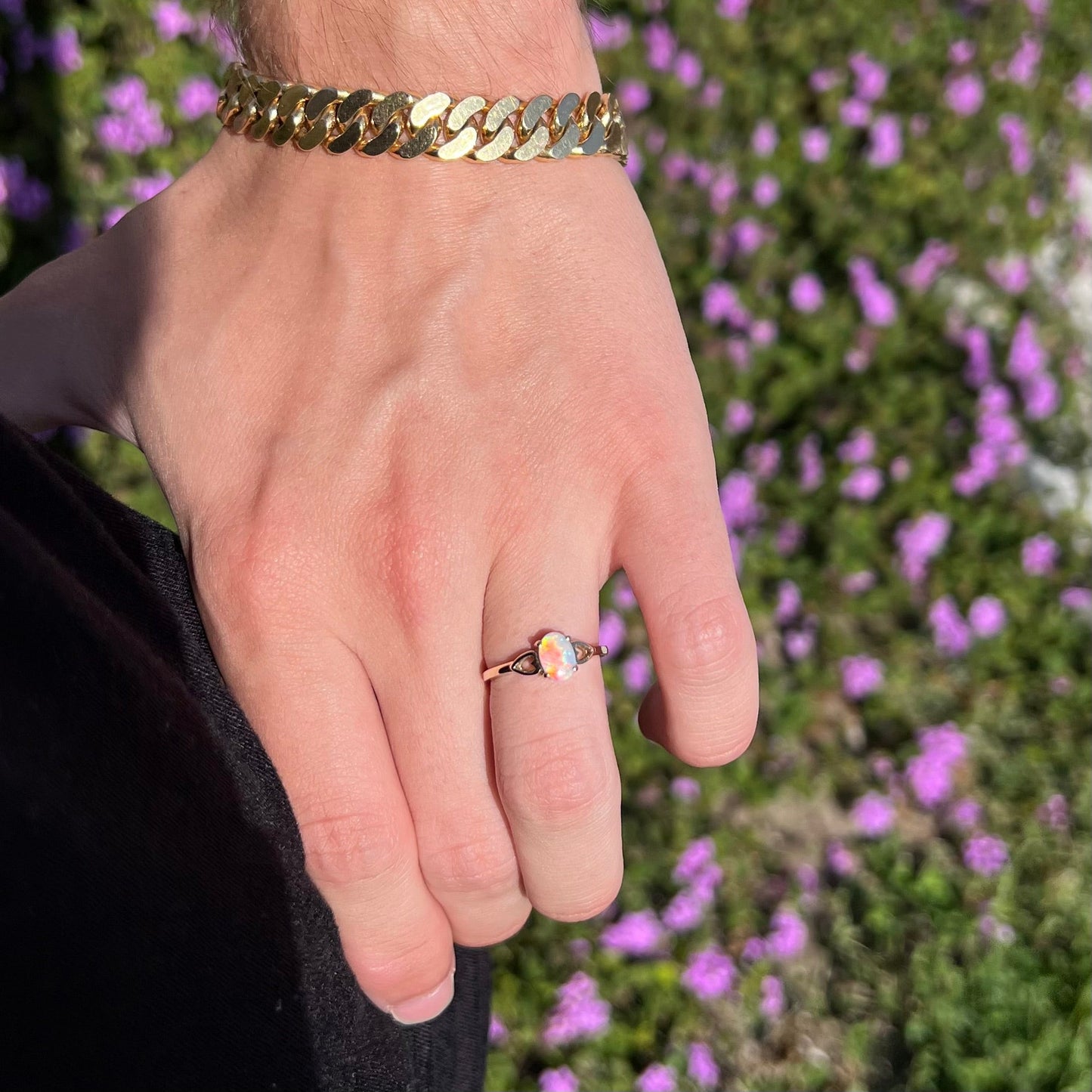 A dainty yellow gold ring mounted with a vivdly bright red Australian opal. The ring has two heart shaped designs.