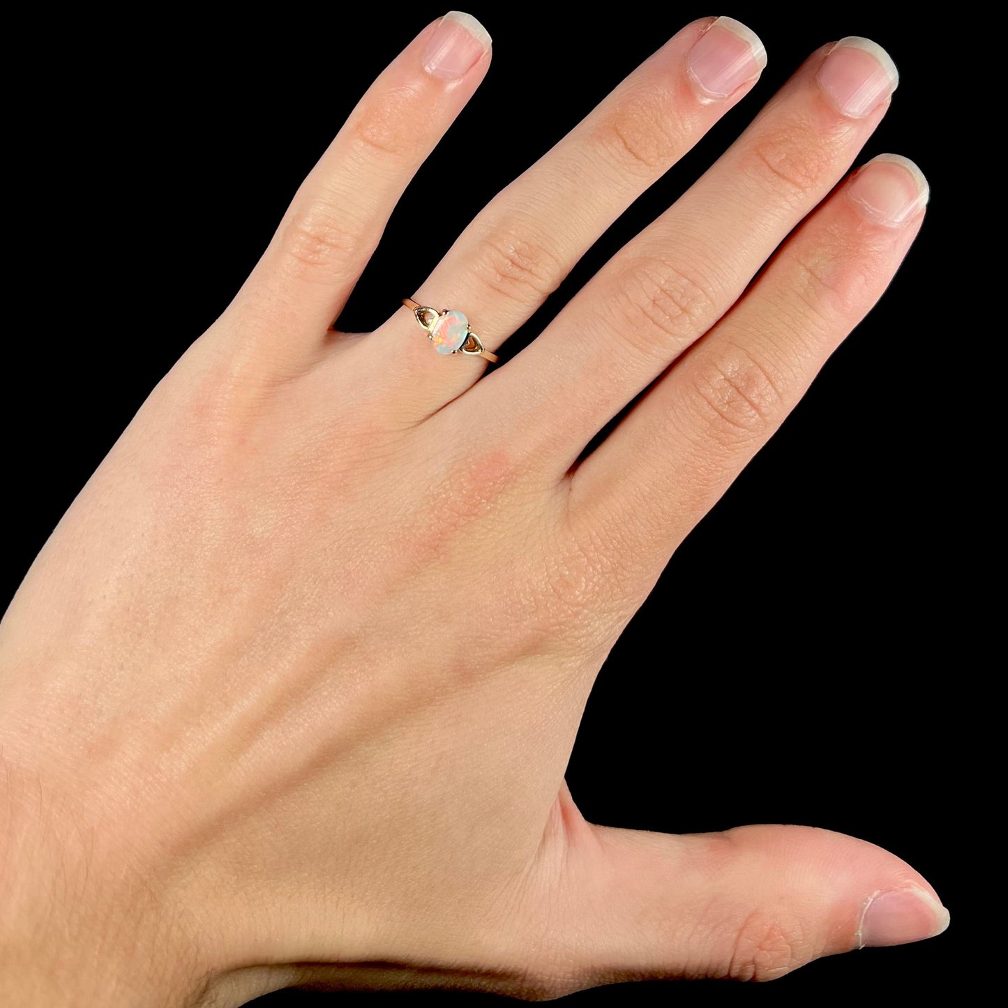 A dainty yellow gold ring mounted with a vivdly bright red Australian opal. The ring has two heart shaped designs.