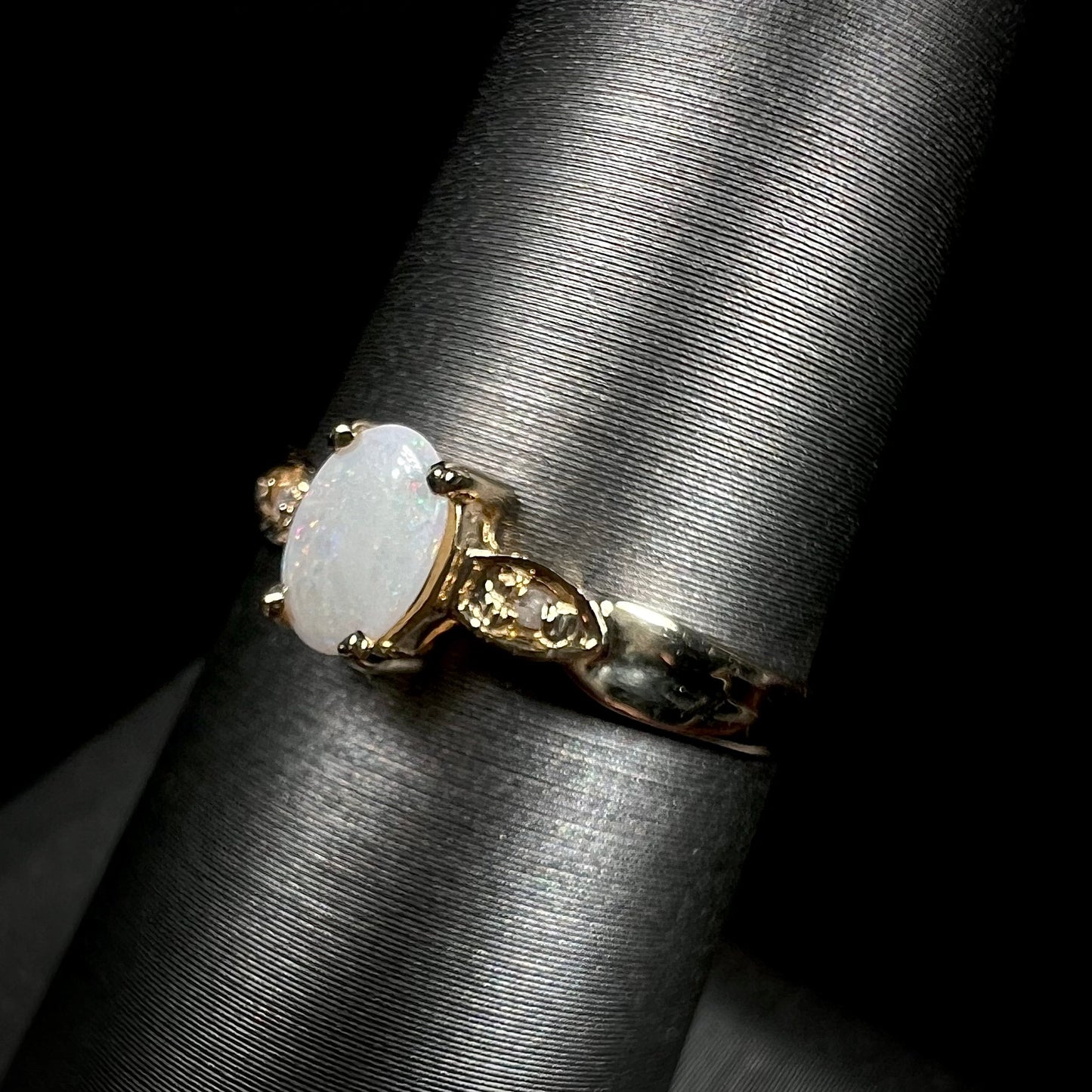A dainty ladies' yellow gold opal and diamond ring. The opal has subtle play of color.
