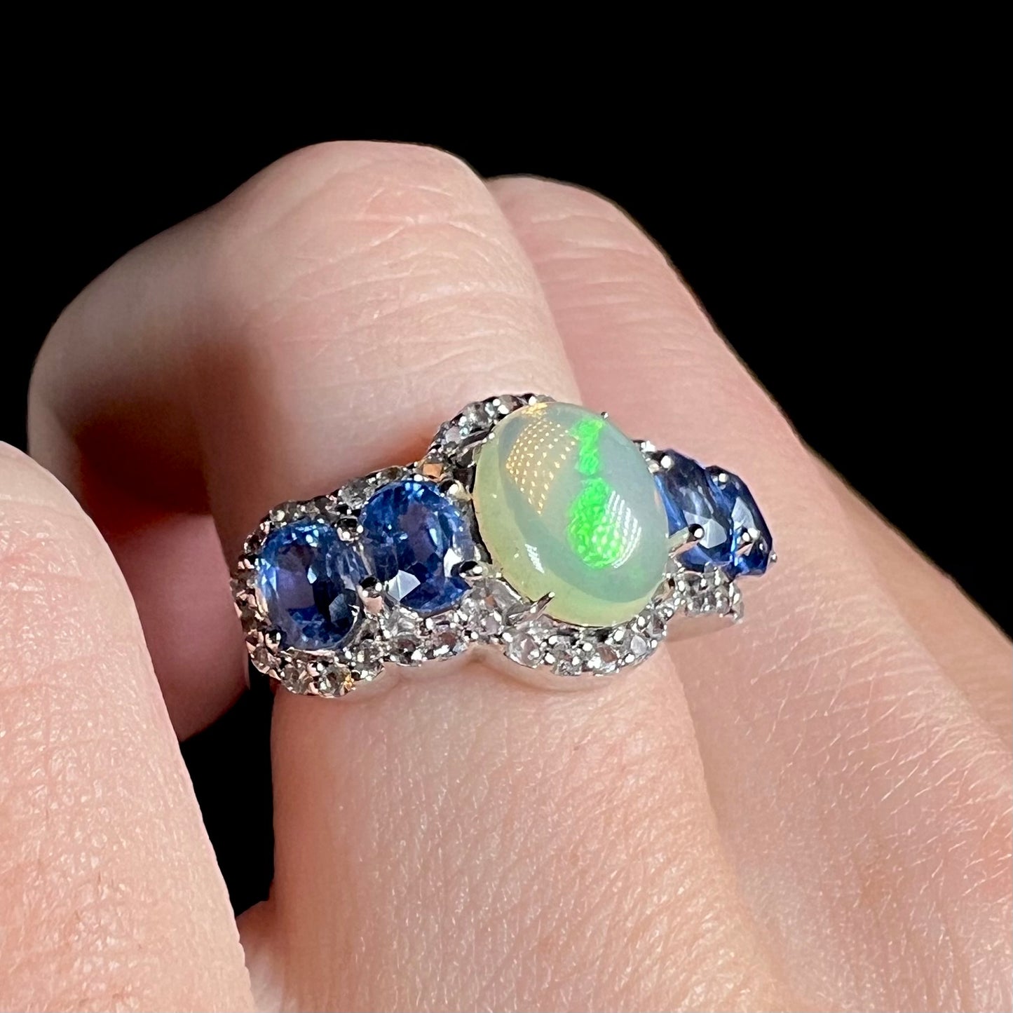 Close-up of a sterling silver Ethiopian opal and kyanite ring worn on a hand.