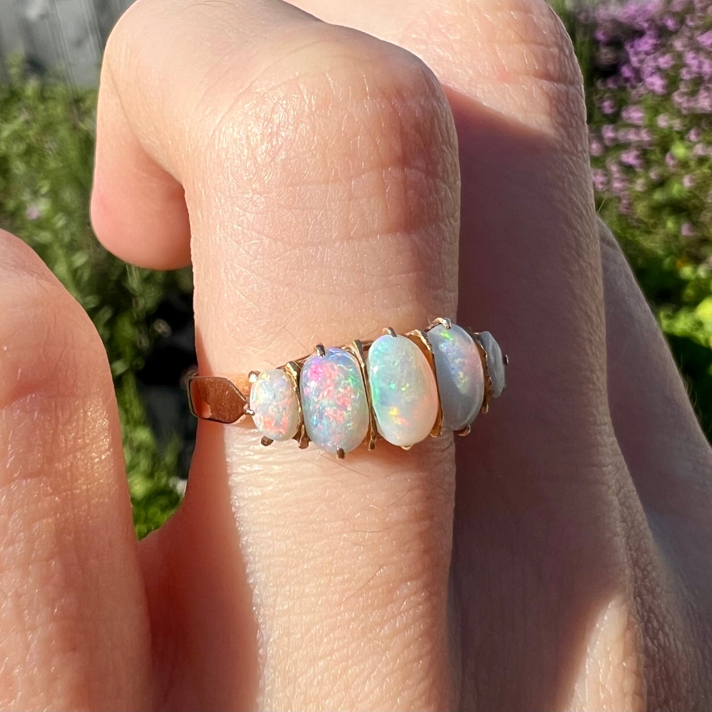 A ladies' Edwardian style 18 karat yellow gold ring set with five natural oval cut opal stones.