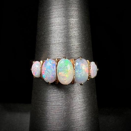 A ladies' Edwardian style 18 karat yellow gold ring set with five natural oval cut opal stones.