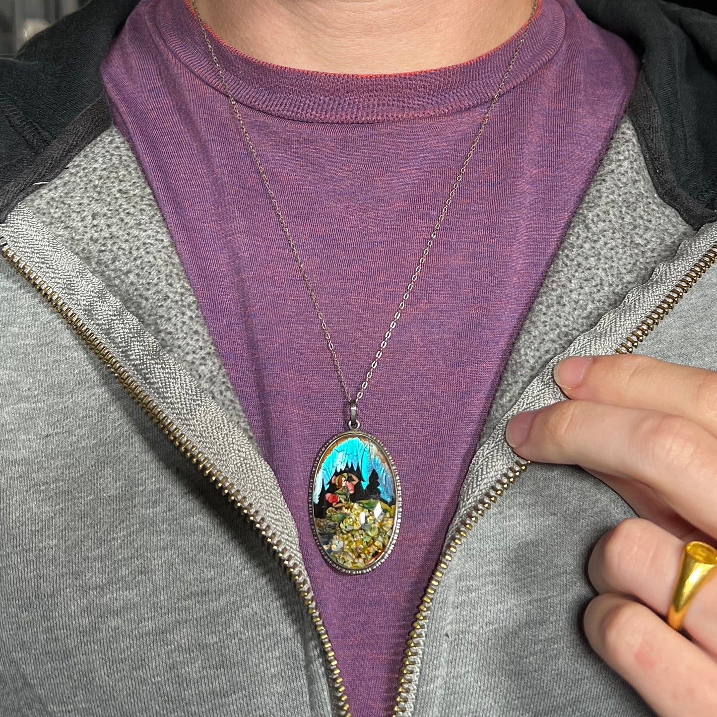 An English sterling silver butterfly wing and opal necklace, worn around a neck against a purple shirt.