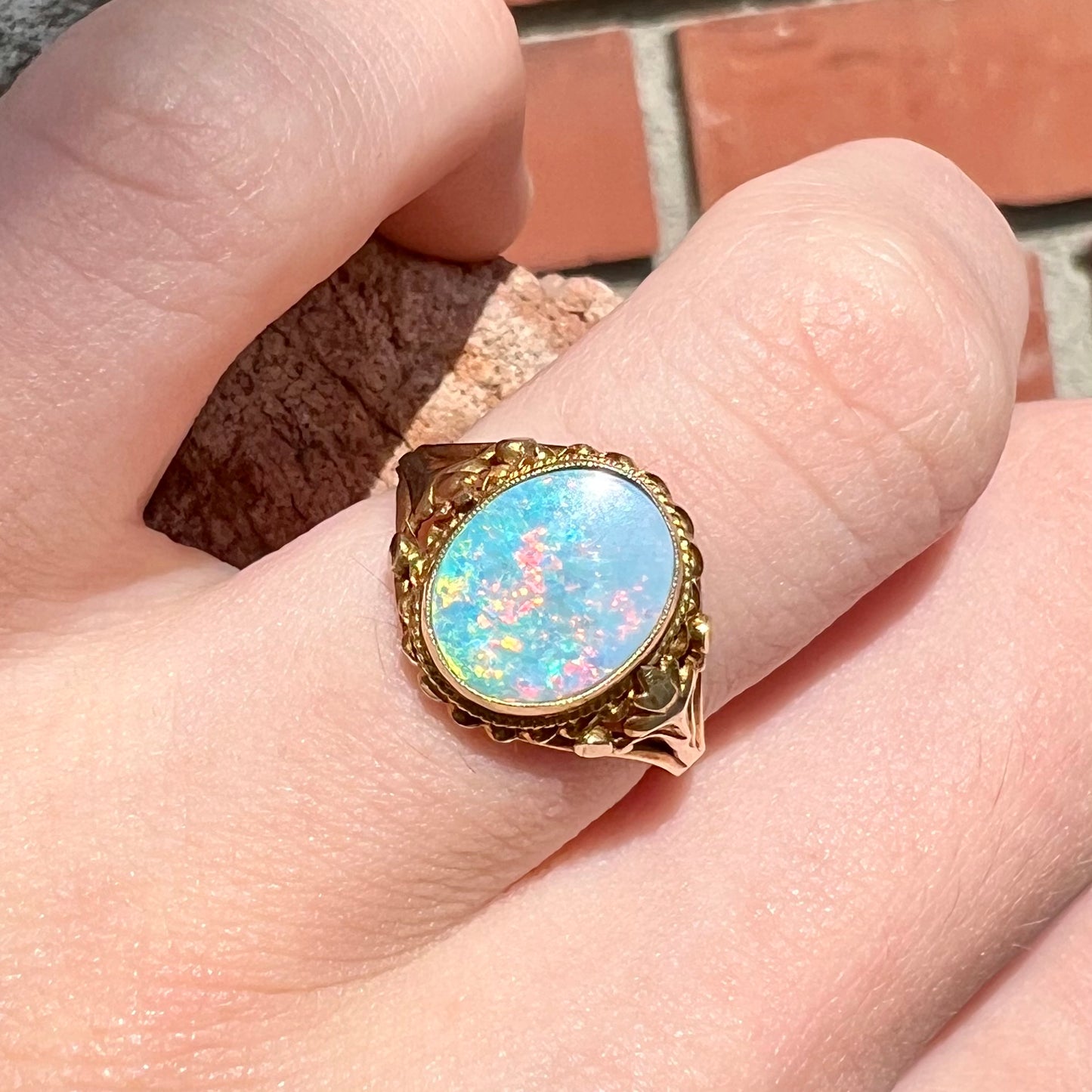 A yellow gold semi-black opal ring with a Victorian fleur-de-lis design.