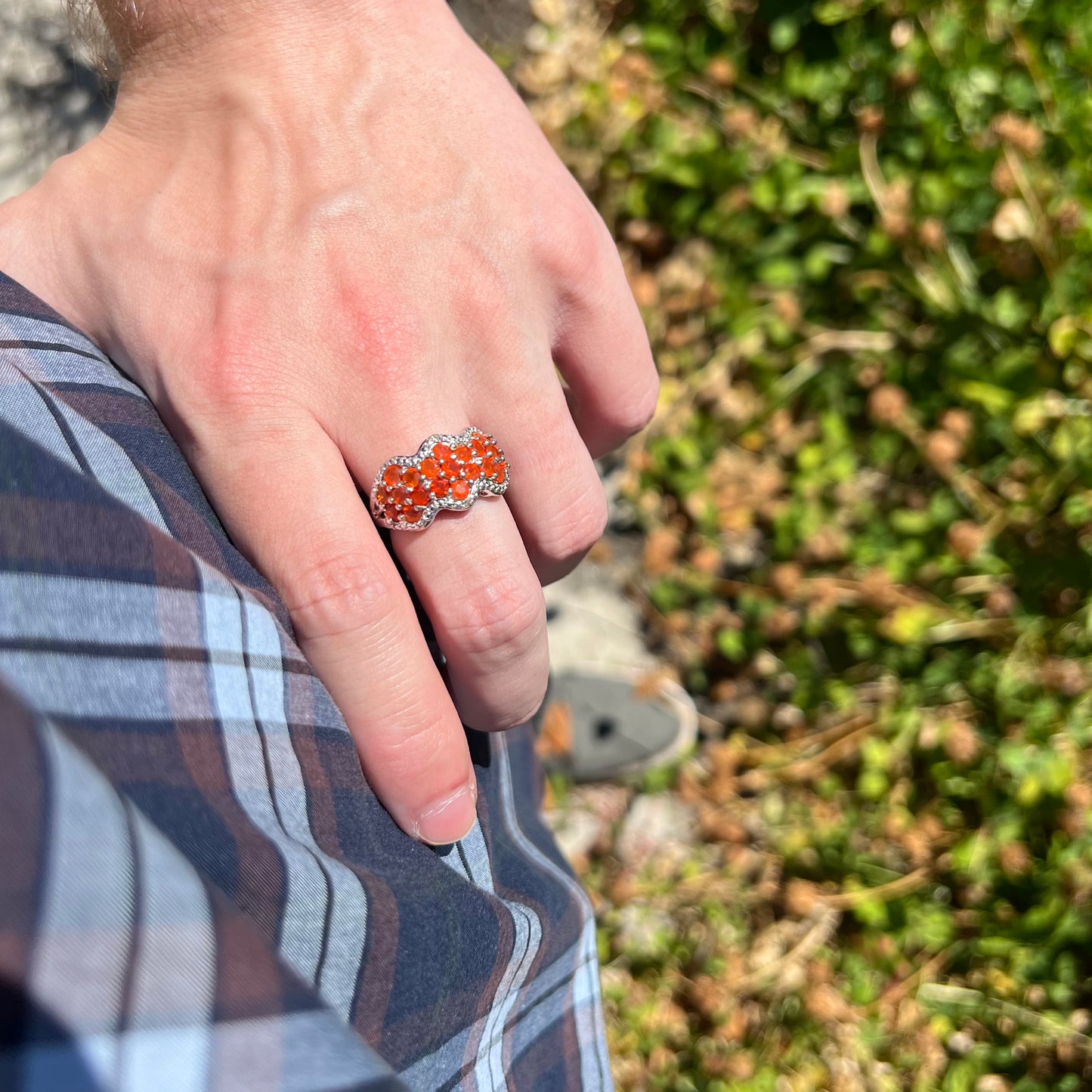 Hand resting on person's hip while wearing an estate women's sterling silver fire opal and diamond-accented ring in sunlight.