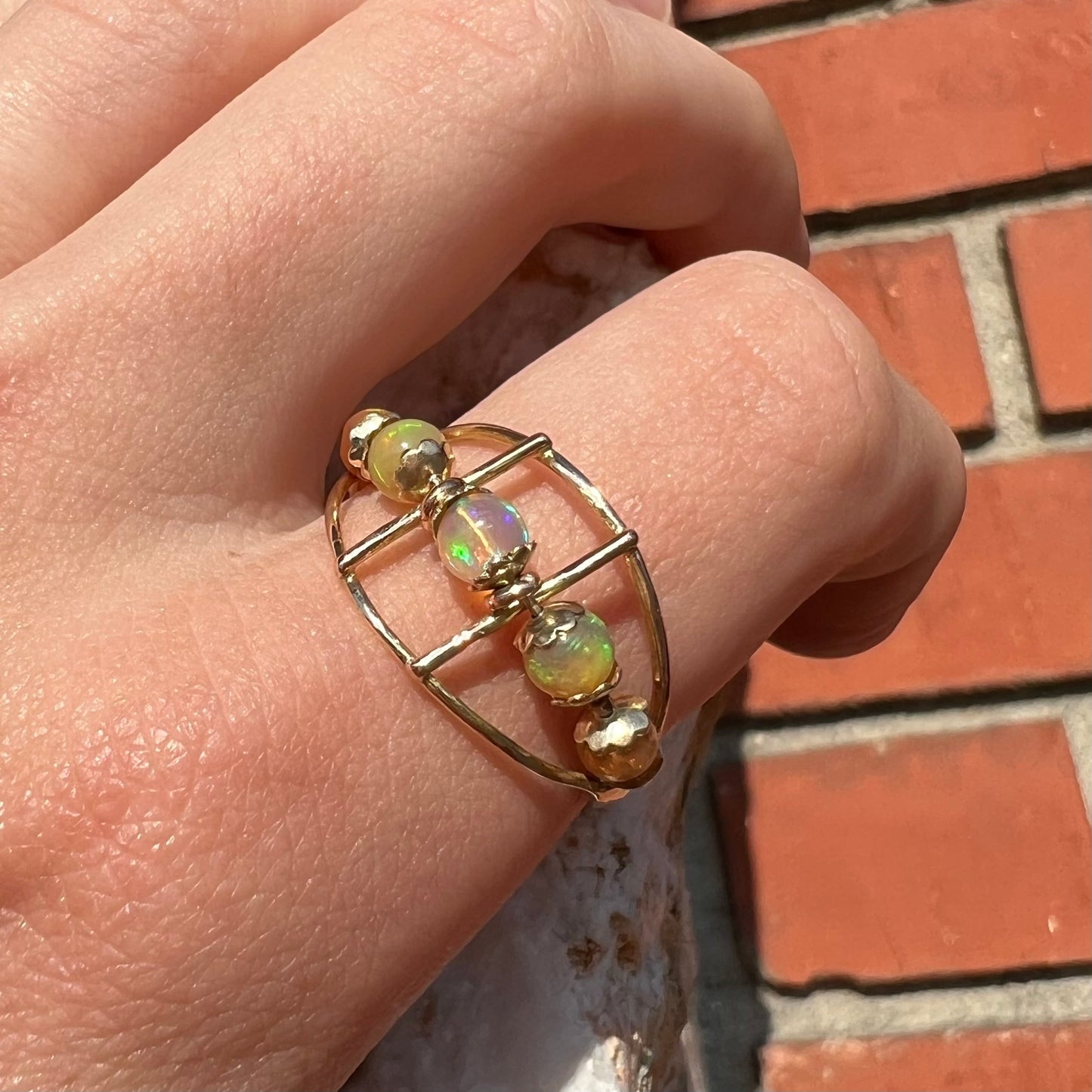 An 18 karat yellow gold ring set with five natural fire opal beads that spin along the ring.