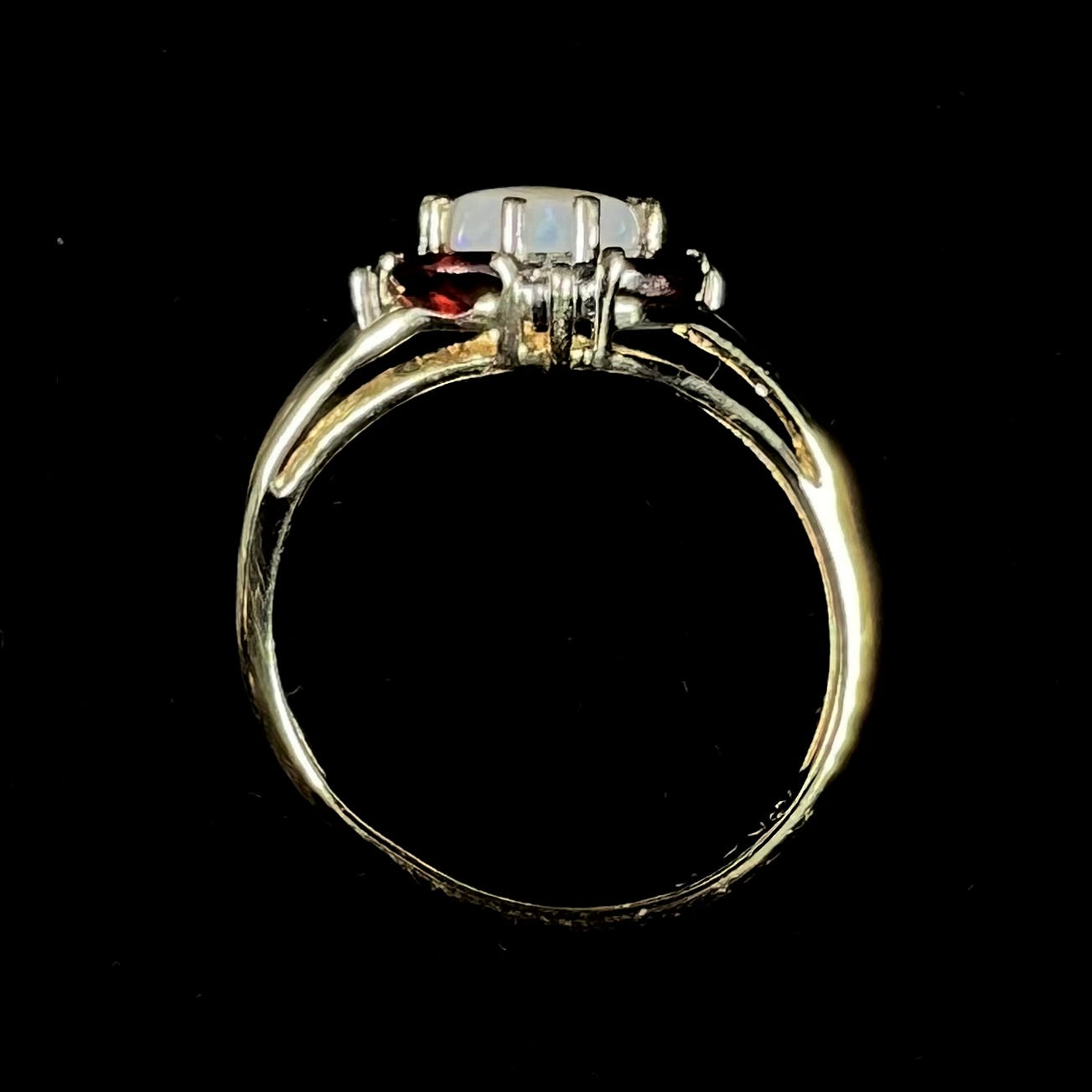 A ladies natural opal ring in yellow gold. The opal is surrounded by red marquise cut garnets and diamonds.