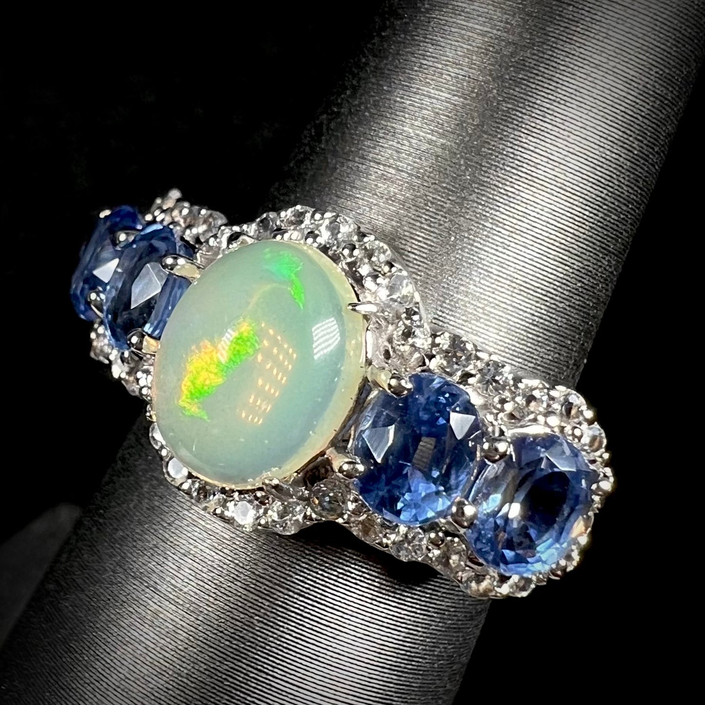 Ethiopian jelly opal and blue kyanite ring, shown at an angle against a black background.