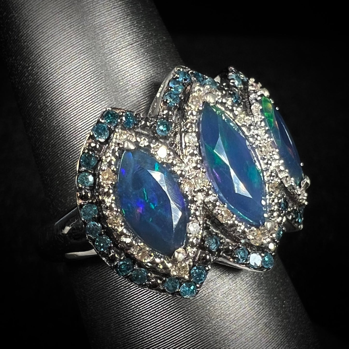 Angled view of a treated Ethiopian opal and blue diamond ring in sterling silver.