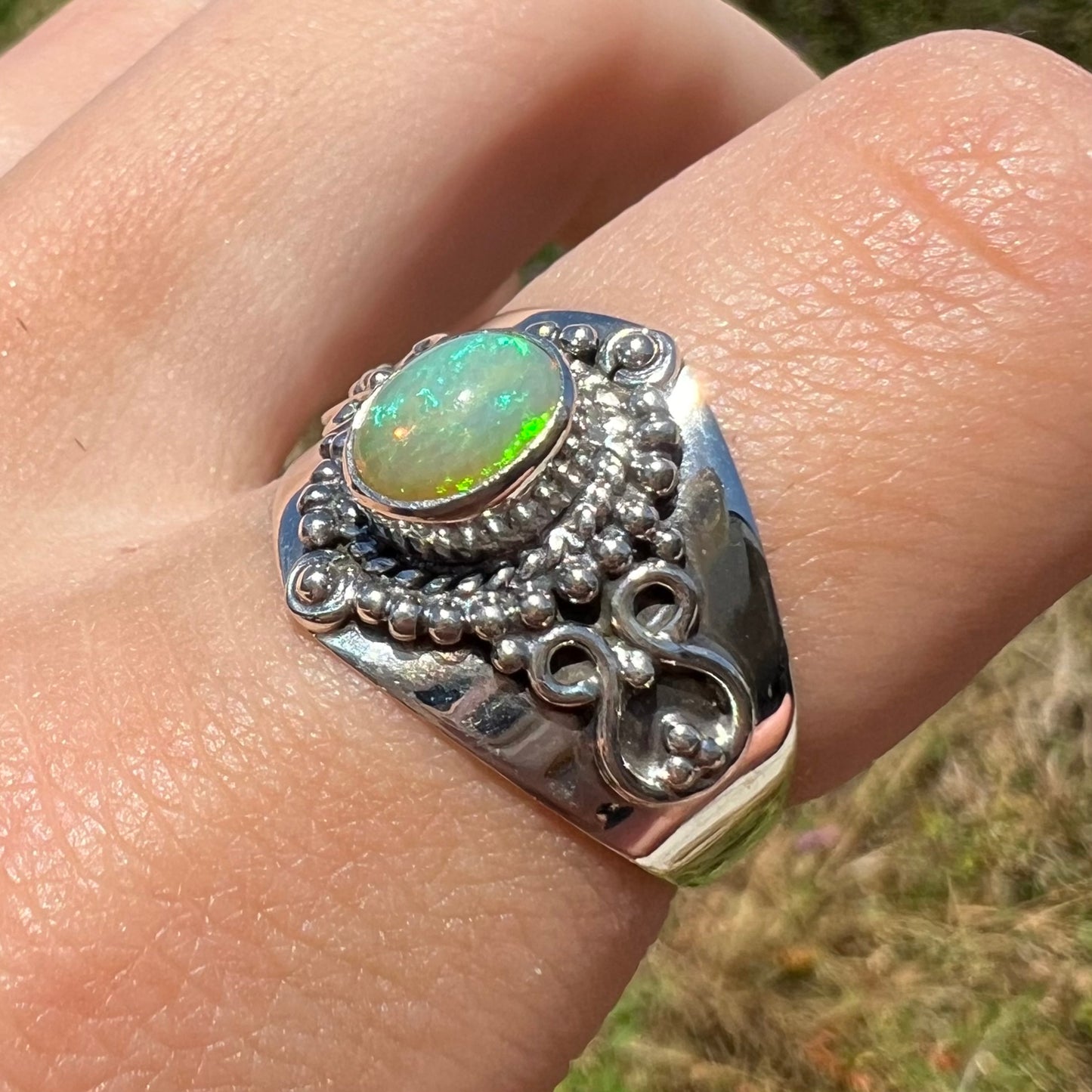 An Ethoipian opal boho ring shown at a macro angle, worn on a finger in sunlight.