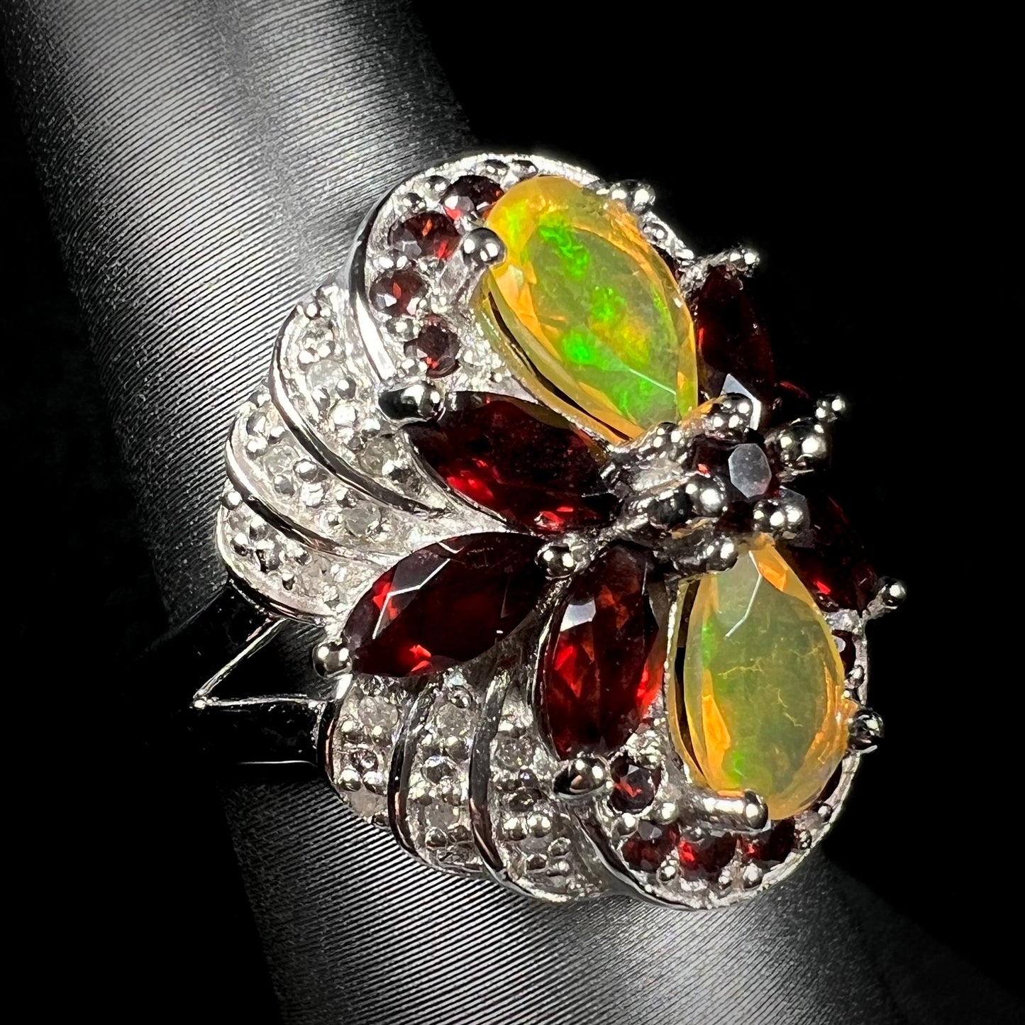 An Ethiopian opal, diamond, and garnet ring made from sterling silver, shown at an angle.