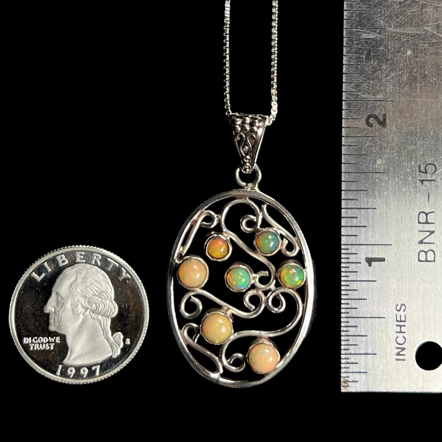 An Ethiopian opal filigree necklace shown next to a quarter and ruler for scale.  It measures almost 2 inches long.