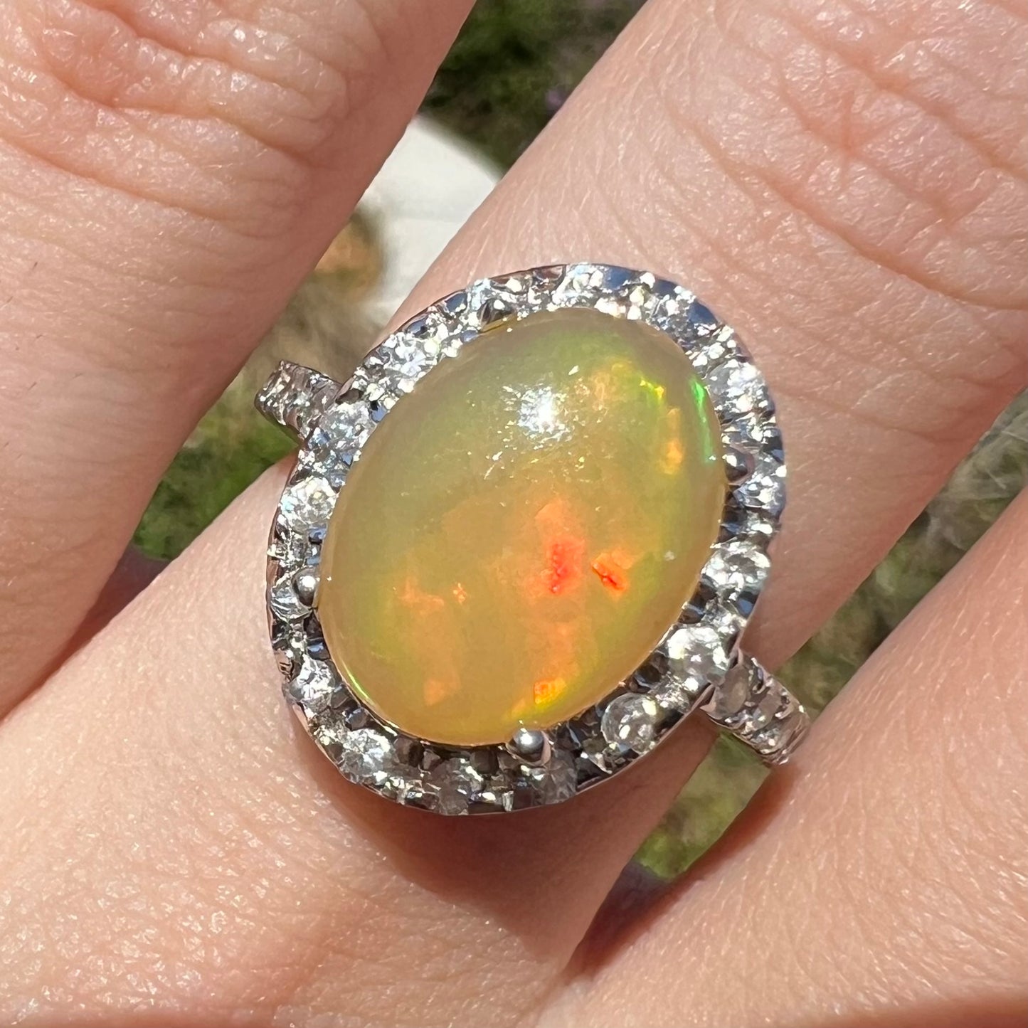 Close-up front view of a sterling silver Ethiopian fire opal ring with a CZ halo.