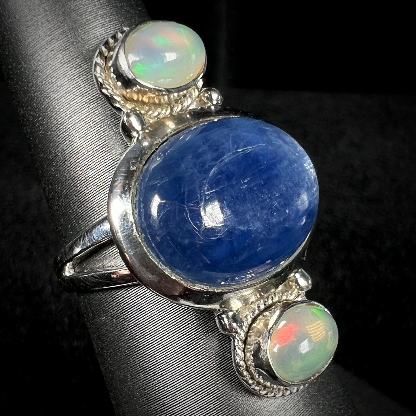 An Ethiopian opal-accented kyanite ring in sterling silver, shown at an angle against dark backdrop.
