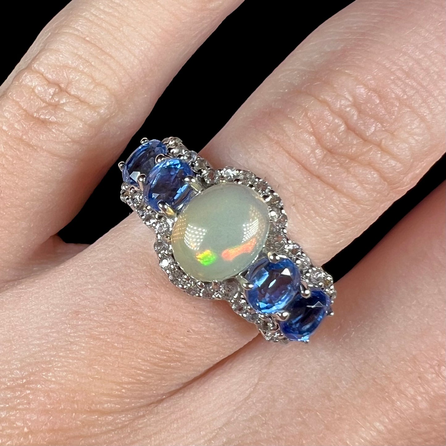 Close-up of a sterling silver Ethiopian opal and kyanite ring worn on a hand.