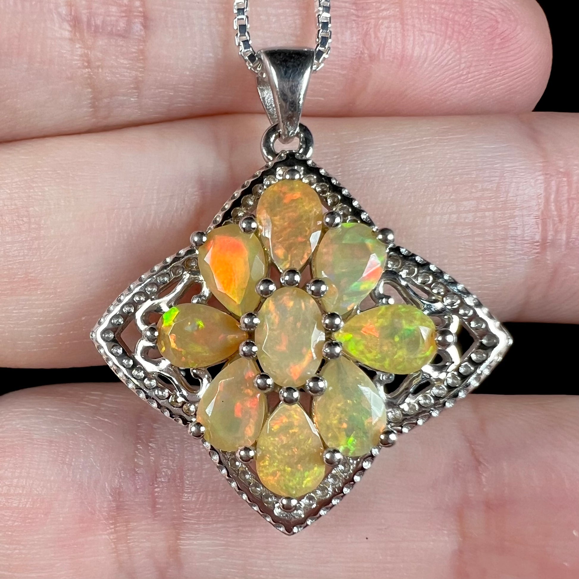An Ethiopian opal star necklace shown close-up in a hand.  The opals have orange and green color play.