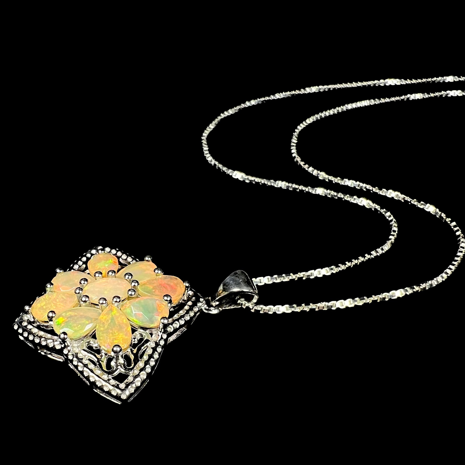 An Ethiopian opal star necklace made from sterling silver, shown at an angle, resting along a black background.