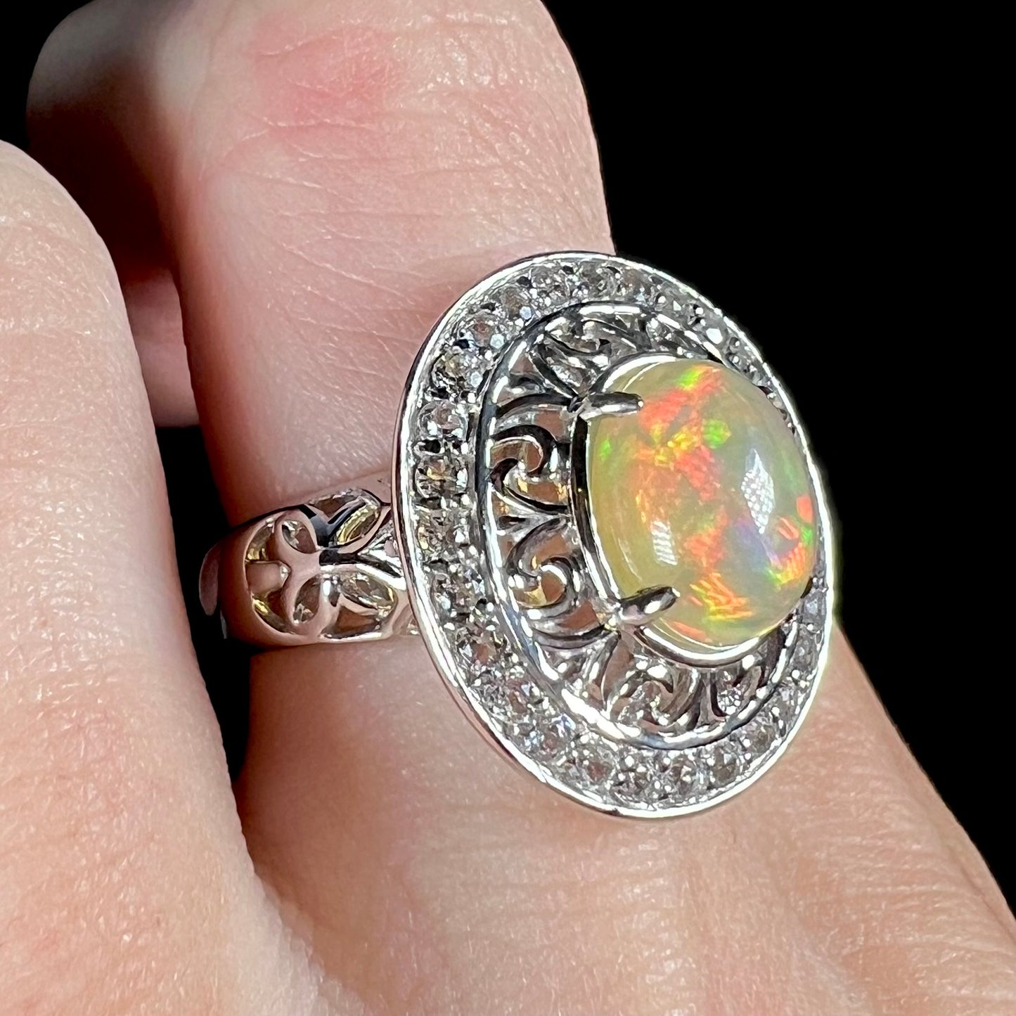 A sterling silver Ethiopian opal halo ring with a double halo of filigree and white topaz accents.
