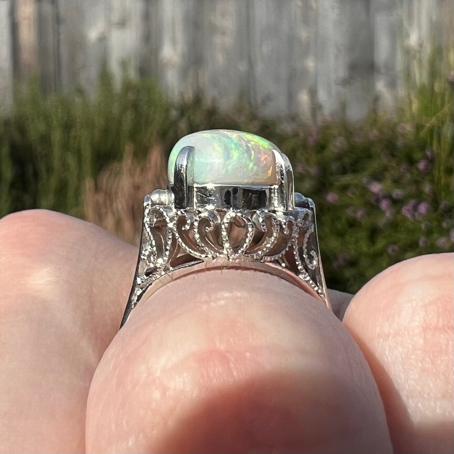 A ladies' Australian opal solitaire engagement ring mounted in platinum. The opal has green and blue colors.